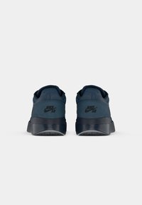 Jūras zilas Nike SB tenisa kurpes ar zamšāda un sieta virsu, ar gumijas zoli un teksturētām akcentiem, redzamas no aizmugures.