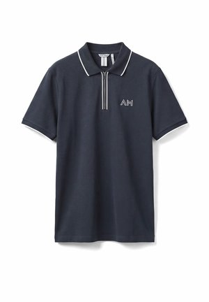 Marineblauw polo met korte mouwen, witte bies op de kraag en mouwen, een rits aan de voorkant, en het "AM"-logo op de linkerborst.