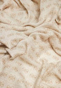 Tessuto beige con un sottile motivo geometrico. Texture morbida, con un design di logo ripetitivo in marrone chiaro su tutta la superficie.