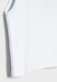 Vit ärmlös topp i mjuk bomull med slät textur och rak fåll. Har minimalistisk design utan synliga mönster eller accenter.
