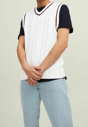 Weißer Strickwesten mit Kabelmustern und einem gerippten Saum, mit V-Ausschnitt und burgunderfarbenen Akzenten, über einem schwarzen Kurzarm-Shirt und hellblauen Jeans.