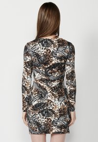 Rochie cu mâneci lungi dintr-un material elastic, având un imprimeu animal și un model paisley, cu o siluetă ajustată și gât rotund.