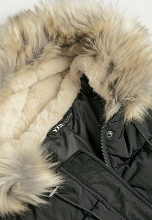 Schwarze Jacke mit einer felligen Kapuze und cremefarbener Innenauskleidung; weiche, plüschige Textur; silberne Beschläge; Reißverschluss; diamantgestepptes Muster.