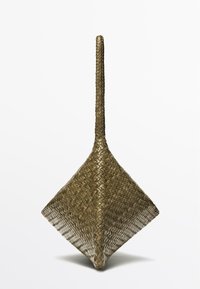 Håndvævet, diamantformet kurv med et langt, smalt håndtag, lavet af naturlige brune fibre mod en hvid baggrund.