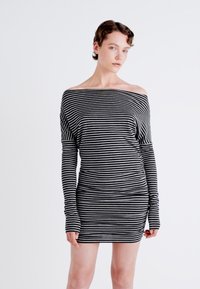 Schulterfreies Kleid in Schwarz und Weiß mit horizontalen Streifen, das eine figurbetonte Silhouette und lange Ärmel mit Daumenlöchern aufweist.