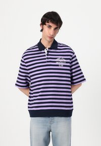 Lilla og marineblå stripete kortermet polo skjorte med krage, som har en hvit brodert logo på venstre bryst og ribbet kant.