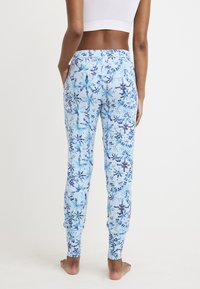 Jogging in tessuto morbido e elasticizzato, con motivo floreale blu su sfondo azzurro, orli aderenti e tasche laterali.