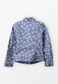 Giacca di jeans blu con stampa floreale bianca, maniche lunghe e polsini con bottoni, mostrata da dietro su uno sfondo bianco.