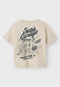 Beige katoenen t-shirt met een marineblauw grafisch ontwerp van een octopus met zonnebril en accenten van banden, tekst luidt "Suzis Garage" en locatiegegevens.