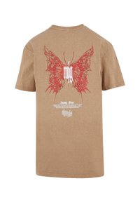 Brown cotton t-shirt featuring a large red butterfly graphic on the back, with white text underneath. Short sleeves and crew neckline.