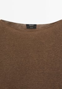 Encolure de chemise en lin marron avec étiquette Massimo Dutti indiquant la marque, fabriqué en Chine, et composition du tissu 100 % lin.