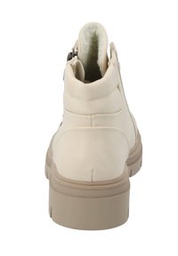 Beiga ankelboots med en slät textur, vadderad krage och sidodragkedja. Tjock, beige gummisula med greppande spår för stabilitet.