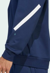 Marineblauwe sweatshirt met een geribde manchette en elastische tailleband, voorzien van een opvallende witte reflecterende streep langs de mouw voor betere zichtbaarheid.