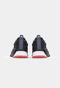 Black and purple training shoes with a mesh upper, padded collars, and a white midsole. Features a textured grip outsole and rear pull tab.