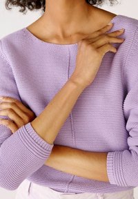 Light purple knitted sweater with a rounded neckline, ribbed cuffs, and textured fabric. Sleeves are slightly loose with a relaxed fit.
