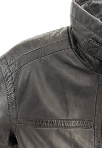 Zwarte leren jas met een hoge kraag, gewatteerde schouderaccenten en een gladde textuur. Zichtbare naden en paneeldetails.