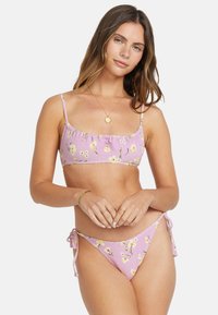 Purple bikini set with floral print. Top features ruffled edges; bottom has adjustable side ties. Striped texture throughout.