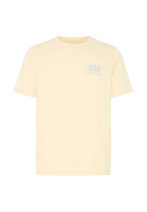 Kreemjas lühikeste varrukatega T-särk, millel on väike sinine lainemuster ja vasaku ülakõhu juures tekst "EXT THE WAVES".