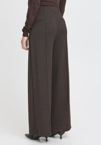 Široke rjave hlače z ribjo kostjo, ki imajo dve zadnji žepni in oprijet pas. Eleganten in prilagojen dizajn.
