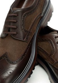 Scarpe eleganti da uomo in pelle e camoscio marrone con dettagli brogue, quattro occhielli, suola a contrasto e finitura testurizzata. Suola esterna antiscivolo in gomma.