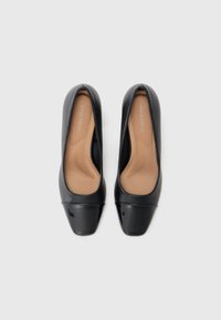 Ballerine nere in pelle con punta arrotondata e punta lucida nera. L'interno presenta un'imbottitura beige con una texture liscia. Il nome del marchio è visibile sulla soletta.