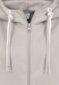 Grijze rits-hoodie gemaakt van zacht materiaal. Voorzien van een hoodie met trekkoord, metalen rits en contrasterende witte trekkoordpunten.