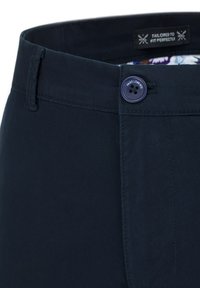 Granatowe spodnie o kroju dopasowanym, z zapięciem na guzik, z wzorzystą podszewką i metką z napisem "Dopasowane idealnie."