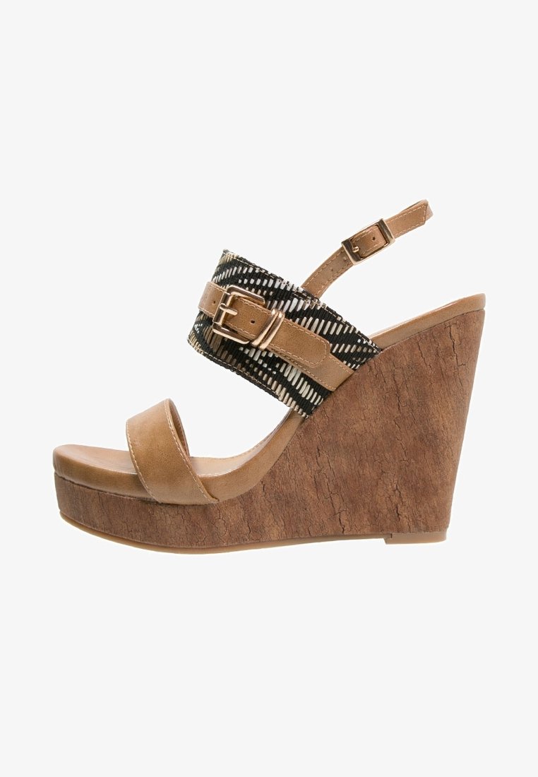 Sandale compensée couleur camel avec plateforme en texture liège, sangle à motif noir et blanc et boucles réglables sur le pied et la cheville.