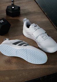 Valkoiset urheilukengät, joissa on harmaat raidat, joissa on tekstuuripinta, nauhakiinnitys ja kuviollinen vaaleansininen pohja.