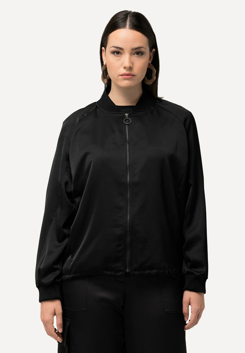 Giacca bomber nera realizzata in tessuto liscio, con zip frontale, colletto a costine e maniche lunghe. Senza motivi o accenti visibili.