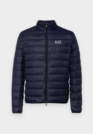 Tumši zils pūkainais mētelis ar rāvējslēdzēju, ar kvadrāta rakstu un stāvošu apkakli. Logo redzams kreisajā krūtīs.