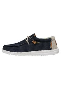 Scarpa da uomo slip-on navy con upper in tessuto testurizzato, suola bianca, dettagli beige e minimal lacing. Presenta un logo sul tallone.