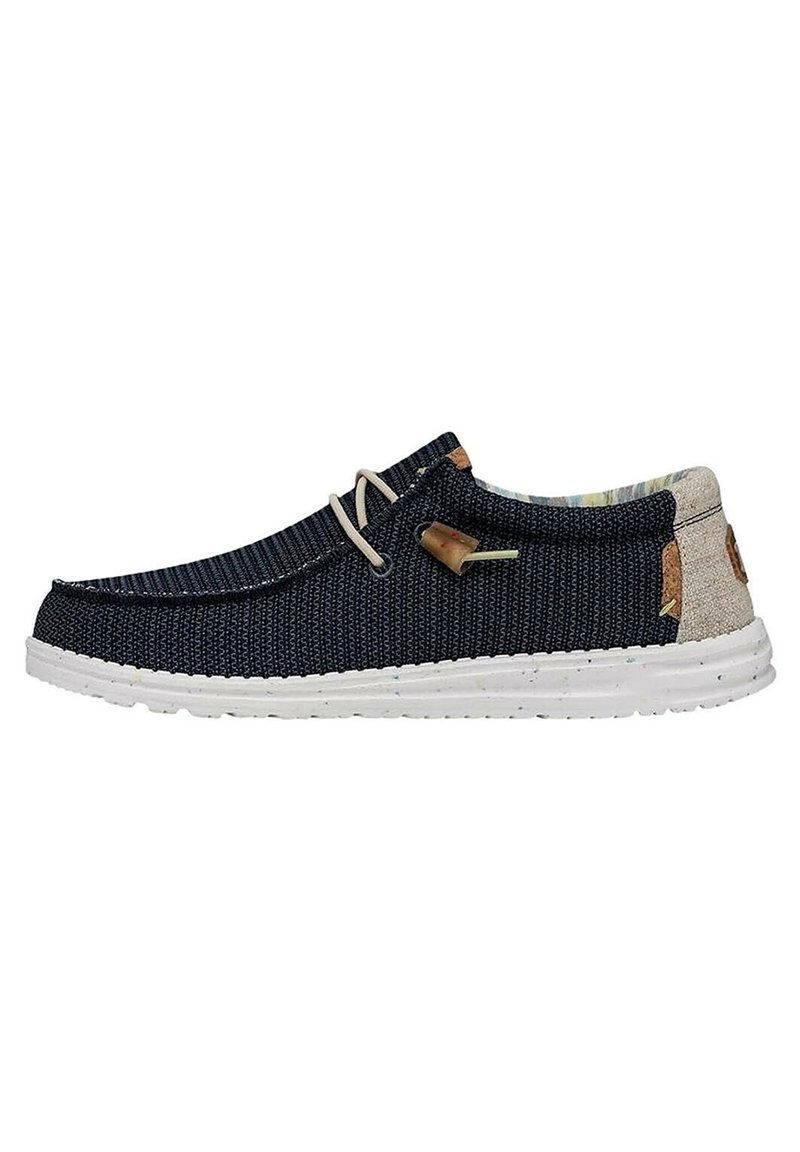 Scarpa da uomo slip-on navy con upper in tessuto testurizzato, suola bianca, dettagli beige e minimal lacing. Presenta un logo sul tallone.