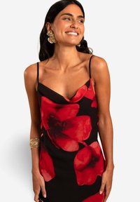 Schwarz Kleid mit rotem Blumenmuster, schulterfreier Ausschnitt, dünne Träger und eine elegante Passform. Das Model hat große goldene Ohrringe und ein Armband getragen.