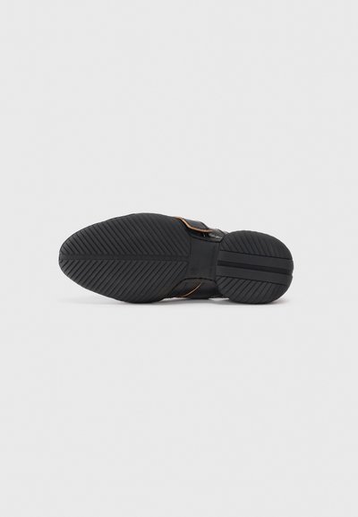 Svart sneaker sula med texturerad gummi för grepp, med en slät övre sektion med kontrasterande detaljer och en sluten design.