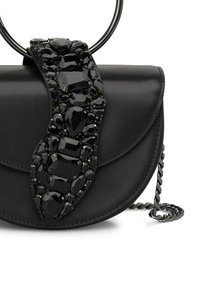 Czarna skórzana torebka o zakrzywionym kształcie. Posiada ozdobę z czarnymi kamieniami oraz srebrny łańcuszek. Gładka faktura, minimalistyczny design.