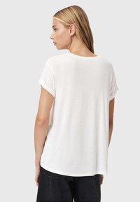 T-shirt bianco a maniche corte con vestibilità ampia, scollatura rotonda e orli arrotolati, realizzato in un tessuto leggermente testurizzato. Cuciture e orlo visibili.