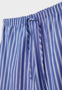 Tissu à rayures verticales bleues et blanches avec une taille élastique et un cordon assorti en tissu noué en un nœud lâche.