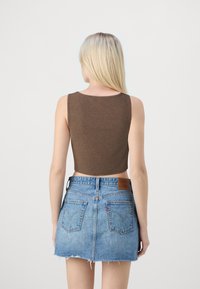 Brązowy prążkowany crop top z okrągłym dekoltem, w połączeniu z jasnoniebieską denimową mini spódnicą z postrzępionymi brzegami i kieszeniami z tyłu.