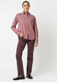 Red and white striped button-up shirt with a front pocket, paired with dark burgundy pants. Worn with black slip-on shoes.