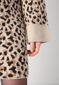 Vestido de malha em bege com padrão de leopardo castanho, apresentando punhos largos em cômodo canelado e um corte descontraído, com tecido texturizado.