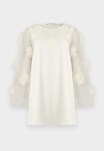 Λευκό φόρεμα με σώμα από απαλό ύφασμα και διαφανείς, ρευστές μανίκες διακοσμημένες με απαλές, τρισδιάστατες ανθισμένες λεπτομέρειες. Στρογγυλή λαιμόκοψη.