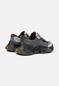 Scarpe sportive grigie con tessuti misti; presentano dettagli scuri, lacci riflettenti e una suola spessa con battistrada in gomma a contrasto.