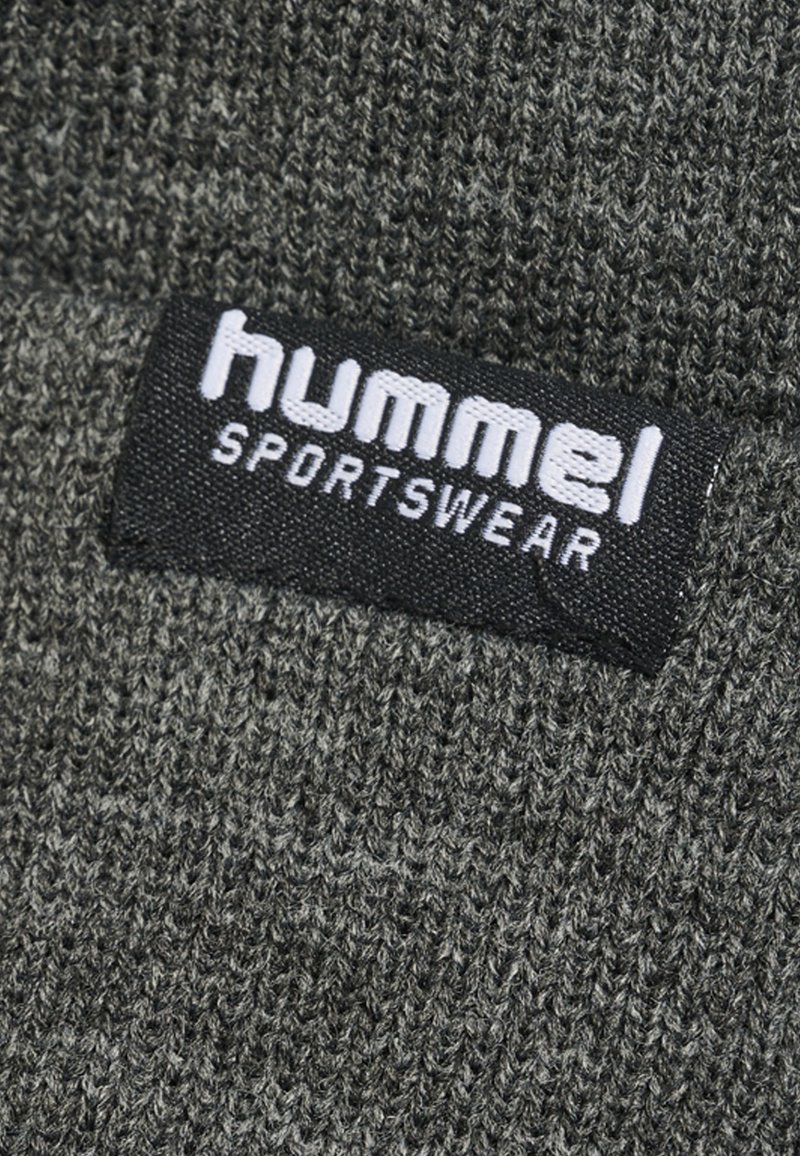 Ciemnoszara dziana tkanina z czarną metką z białym napisem "hummel SPORTSWEAR". Teksturowana powierzchnia o miękkim wyglądzie.