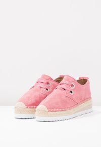 Chaussures en daim rose avec une semelle compensée, agrémentées d'un détail en jute tressé et d'œillets en métal pour les lacets, dans un design décontracté.