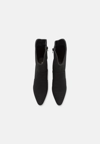 Czarne botki za kostkę z ostrym noskiem, wykonane z gładkiego materiału. Posiadają boczny zamek błyskawiczny oraz elegancki, minimalistyczny design.