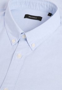 Chemise bleu clair boutonnée avec des boutons blancs et un col moyen écarté, affichant l'étiquette de marque "Matinique" et l'étiquette de taille "L".