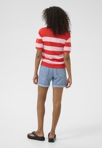 Red and pink striped short-sleeve sweater paired with light blue rolled-up denim shorts and black platform sandals.