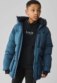 Veste bleue rembourrée avec une capuche amovible, présentant des poignets côtelés, des poches zippées et un sweat à capuche noir en dessous avec un imprimé de logo.