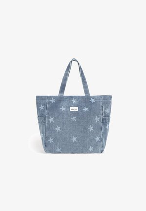 Sac tote en denim bleu avec des motifs d'étoiles clairs, deux bretelles, des poches latérales et une petite étiquette "Brownie" au centre avant.